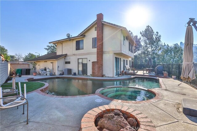 back of house featuring central air condition unit, a patio, and a swimming pool with hot tub