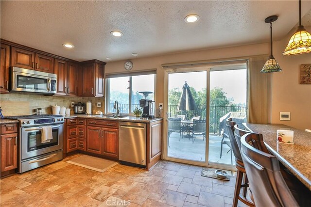 kitchen with decorative light fixtures, stainless steel appliances, a textured ceiling, and sink