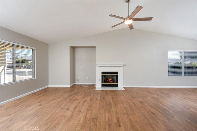 unfurnished living room featuring ceiling fan, a fireplace, lofted ceiling with beams, and light wood-type flooring