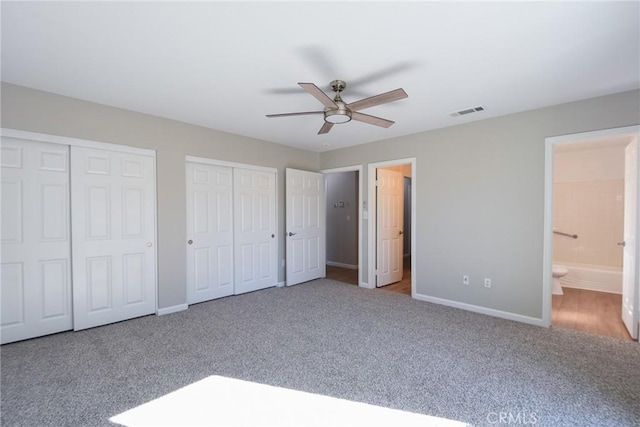 unfurnished bedroom with light carpet, ensuite bath, ceiling fan, and multiple closets