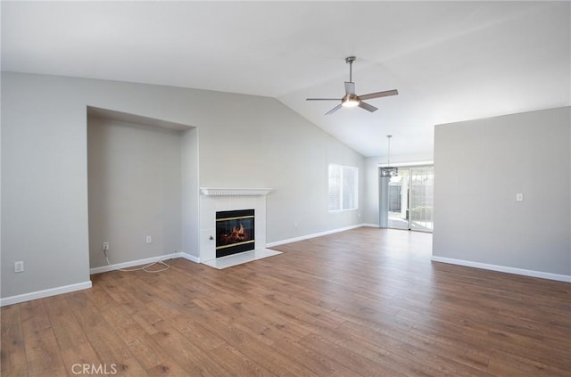 unfurnished living room featuring hardwood / wood-style floors, ceiling fan, vaulted ceiling, and a tiled fireplace