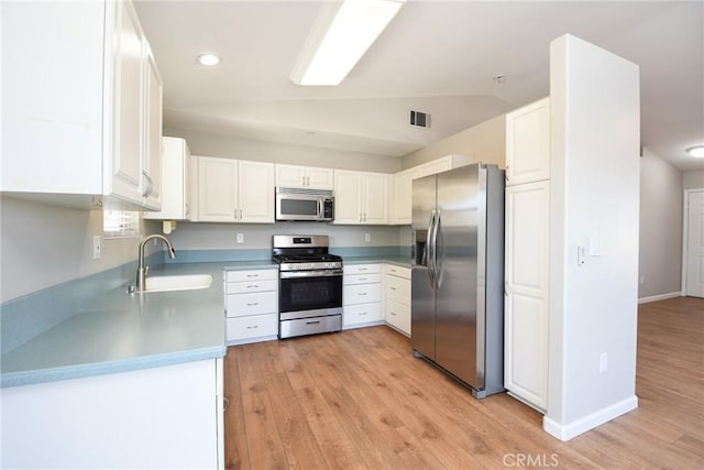 kitchen with white cabinetry, sink, light hardwood / wood-style floors, lofted ceiling, and appliances with stainless steel finishes