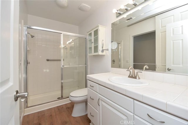 bathroom with hardwood / wood-style floors, toilet, an enclosed shower, and vanity