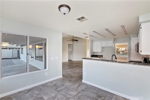 kitchen featuring white cabinetry, ceiling fan, sink, dark stone countertops, and stove