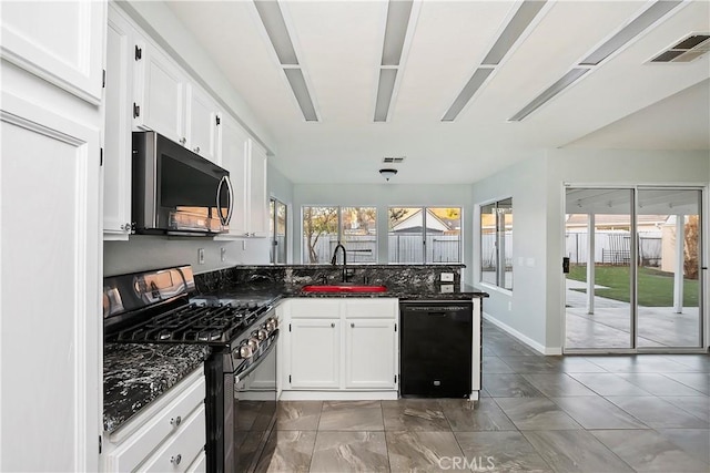 kitchen featuring kitchen peninsula, sink, black appliances, dark stone countertops, and white cabinetry