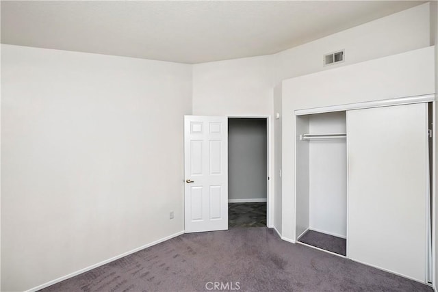 unfurnished bedroom with dark colored carpet and a closet