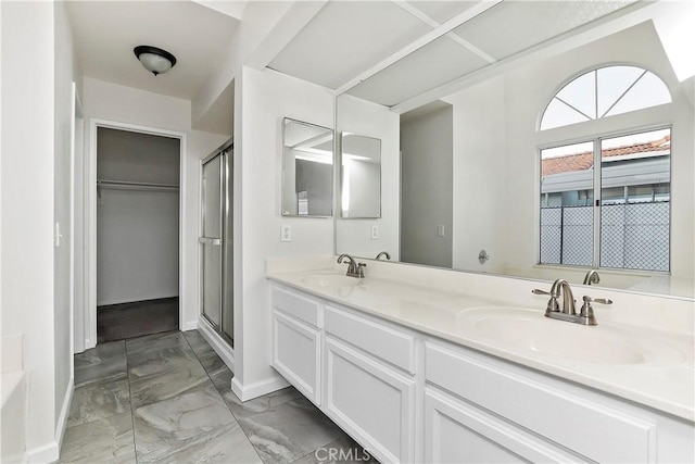 bathroom featuring a shower with door and vanity