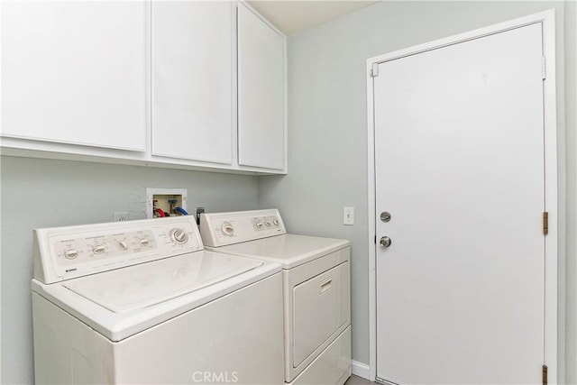 clothes washing area with washing machine and dryer and cabinets