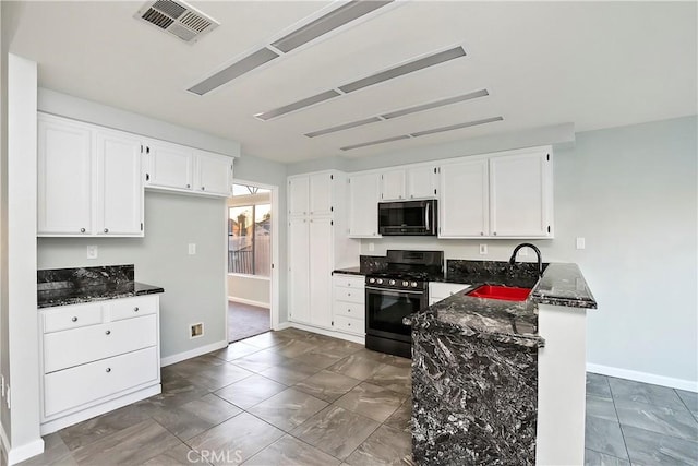 kitchen featuring stainless steel range with gas cooktop, sink, white cabinets, and dark stone counters