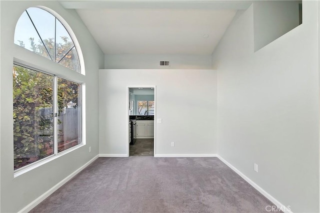 unfurnished room featuring carpet floors and high vaulted ceiling