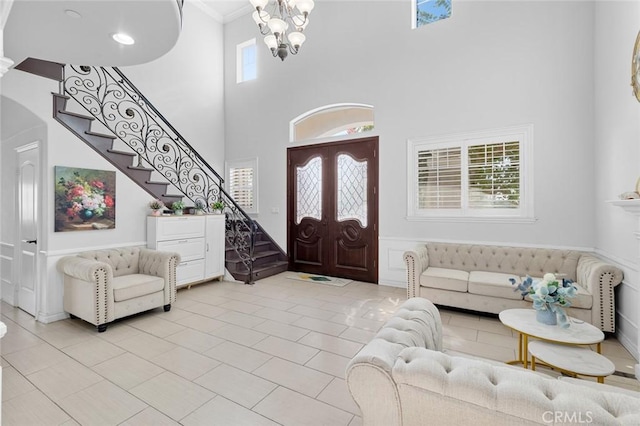 tiled entryway with a high ceiling, an inviting chandelier, and ornamental molding