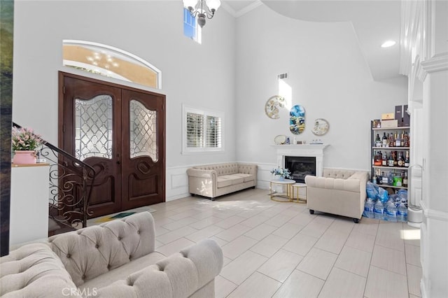 entryway featuring a high ceiling, light tile patterned flooring, a notable chandelier, and crown molding