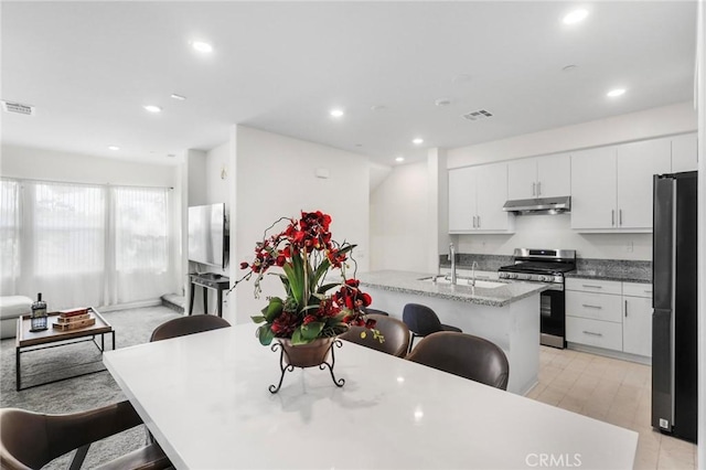 kitchen with a kitchen breakfast bar, sink, white cabinetry, and stainless steel appliances