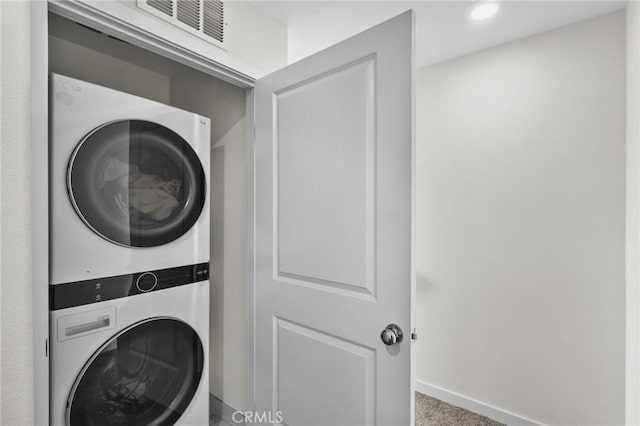 laundry area featuring carpet flooring and stacked washer and clothes dryer