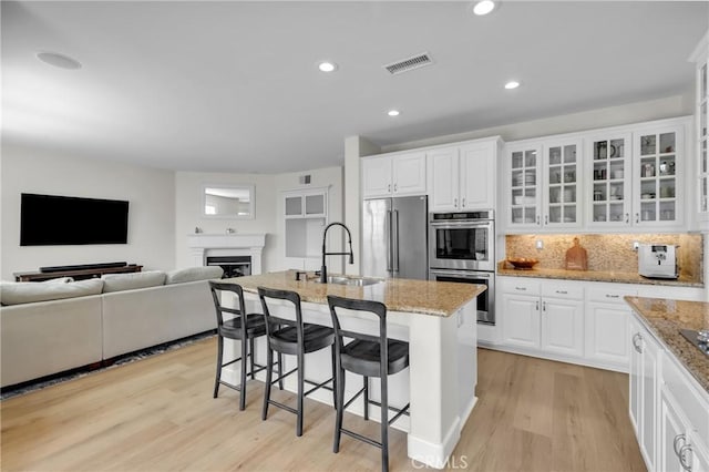 kitchen featuring appliances with stainless steel finishes, an island with sink, white cabinetry, and sink