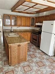 kitchen with white fridge, sink, kitchen peninsula, and range with electric cooktop