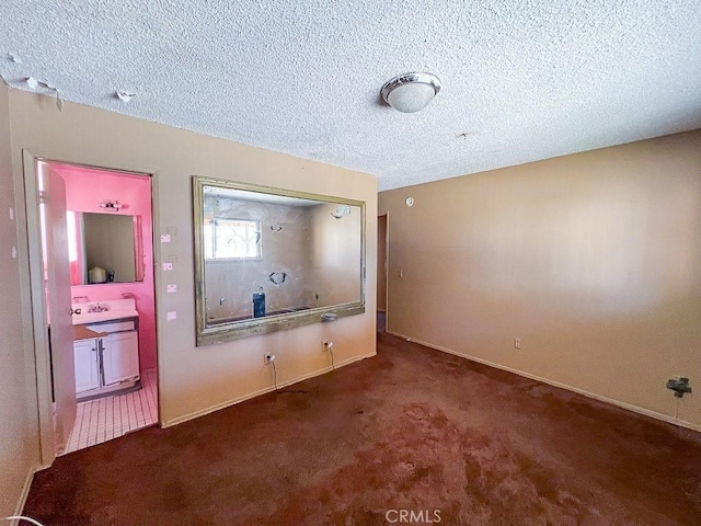 unfurnished bedroom with sink, dark colored carpet, and a textured ceiling