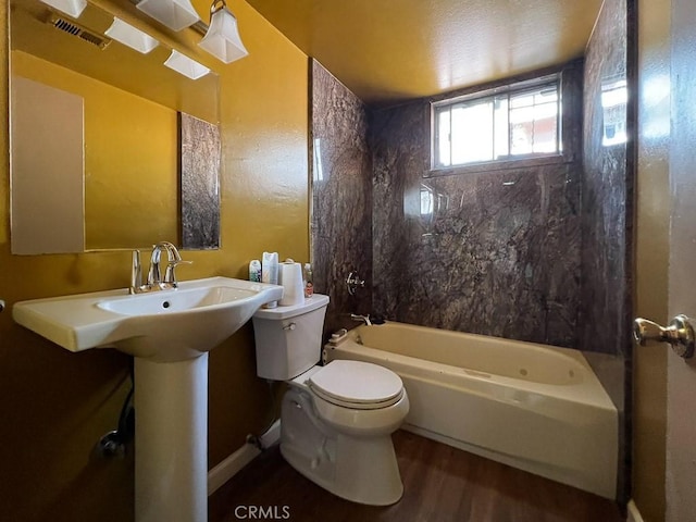 bathroom with wood-type flooring, toilet, and tiled shower / bath combo