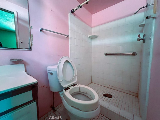 bathroom with a tile shower, toilet, tile patterned flooring, and vanity