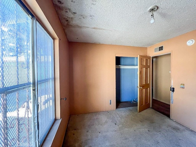 unfurnished bedroom with a closet, light colored carpet, and a textured ceiling