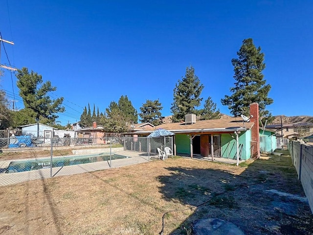 rear view of house featuring a fenced in pool and a yard