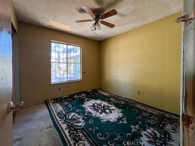 carpeted empty room with ceiling fan and a textured ceiling