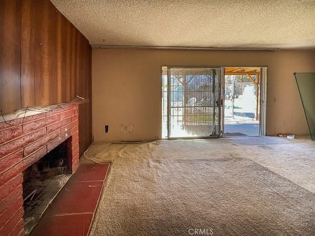 unfurnished living room featuring a fireplace, wood walls, a textured ceiling, and carpet floors