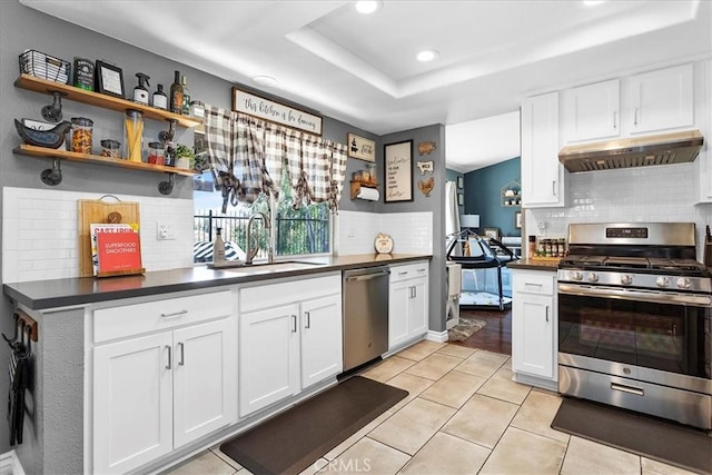 kitchen featuring white cabinetry, sink, range hood, backsplash, and appliances with stainless steel finishes