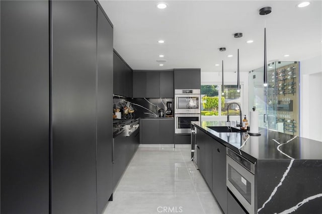 kitchen with backsplash, sink, hanging light fixtures, stainless steel appliances, and light tile patterned floors