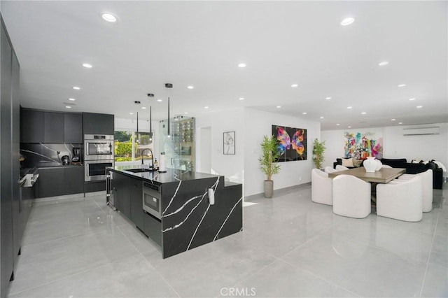 kitchen featuring a wall unit AC, sink, appliances with stainless steel finishes, a large island, and light tile patterned floors