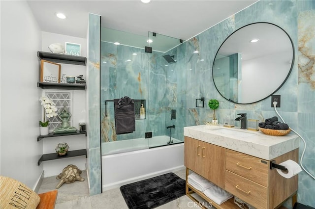 bathroom with tile walls, enclosed tub / shower combo, and vanity