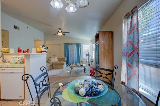 dining space with ceiling fan with notable chandelier, light tile patterned floors, sink, and vaulted ceiling