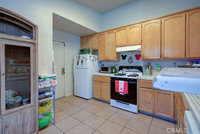 kitchen with tile counters, light tile patterned flooring, and white appliances