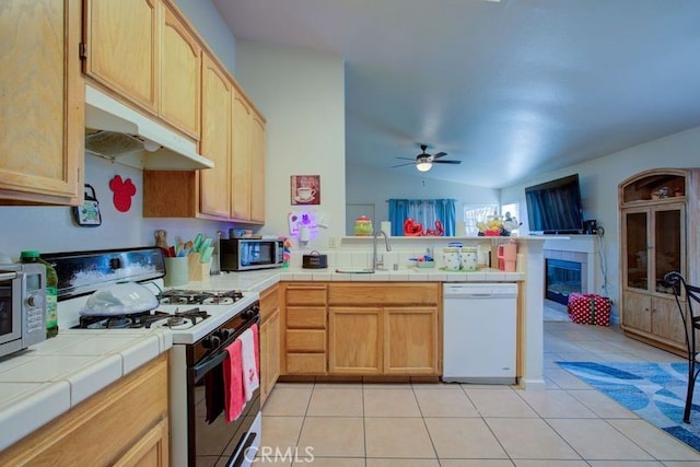 kitchen featuring ceiling fan, tile counters, sink, white appliances, and light tile patterned floors