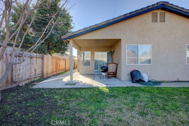 rear view of property featuring a yard and a patio area