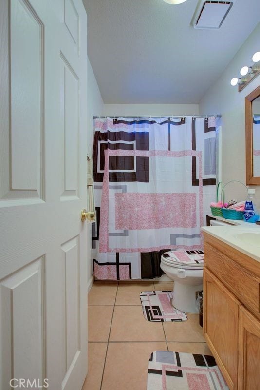 bathroom with toilet, vanity, and tile patterned floors