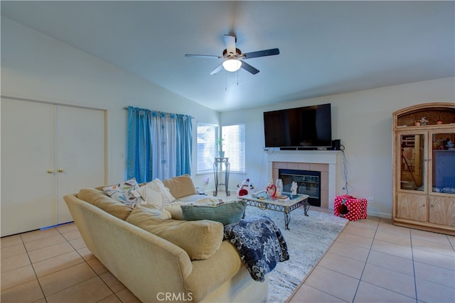 tiled living room featuring a tile fireplace, vaulted ceiling, and ceiling fan