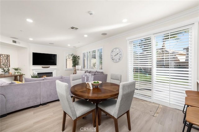 dining space with crown molding and light hardwood / wood-style flooring