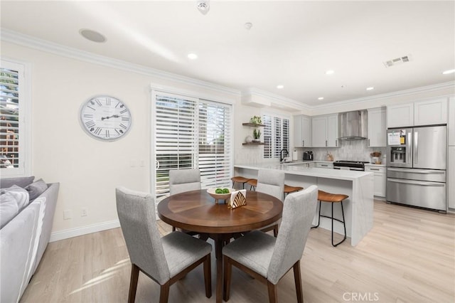 dining area with light hardwood / wood-style flooring, crown molding, and sink