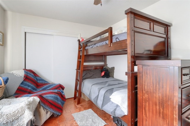 tiled bedroom featuring ceiling fan and a closet