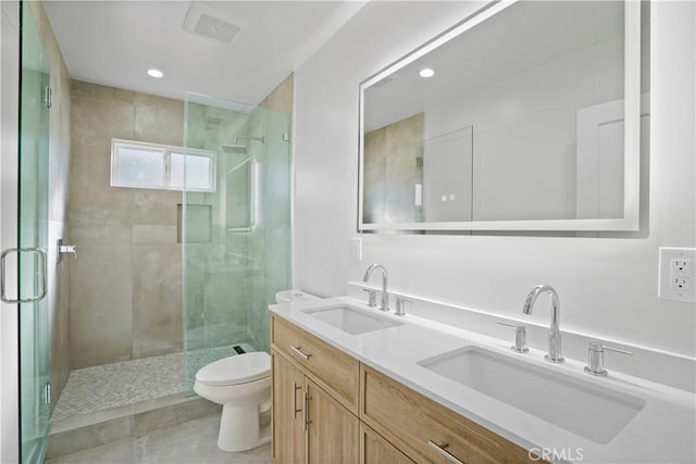 bathroom featuring a shower with door, vanity, and toilet