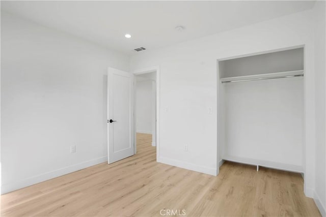 unfurnished bedroom featuring light hardwood / wood-style floors and a closet