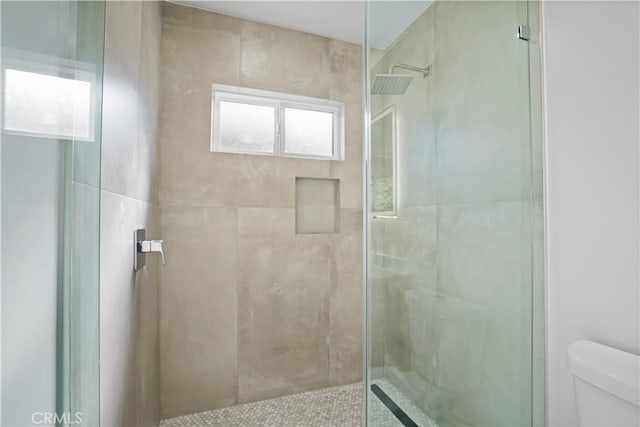 bathroom featuring toilet and a shower with shower door