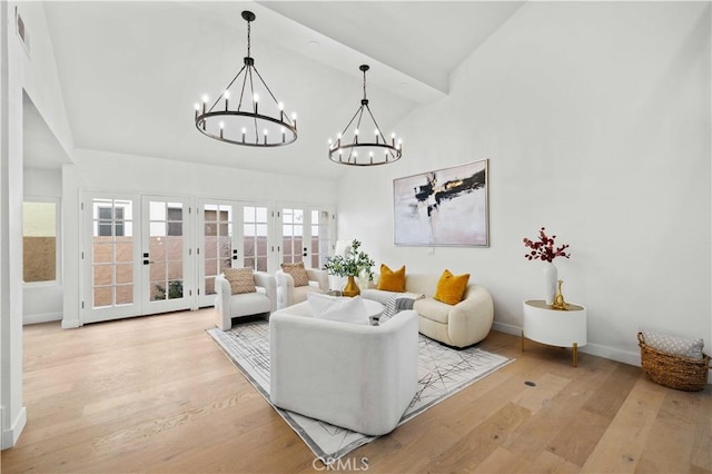 living room featuring high vaulted ceiling, french doors, an inviting chandelier, and light hardwood / wood-style flooring