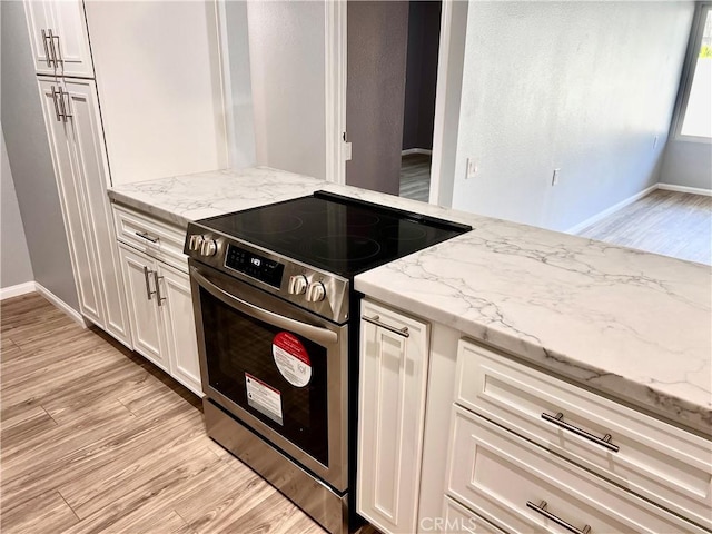 kitchen featuring white cabinetry, light stone countertops, stainless steel range with electric cooktop, and light wood-type flooring