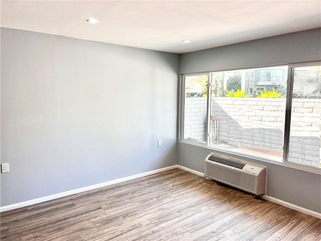 empty room featuring a wall unit AC and light hardwood / wood-style floors