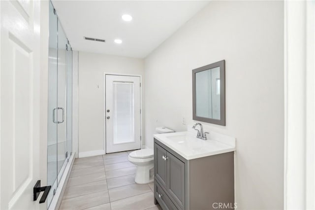 bathroom with tile patterned flooring, vanity, toilet, and walk in shower