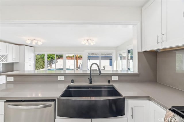 kitchen featuring stainless steel dishwasher, white cabinetry, sink, and range