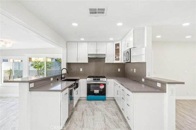 kitchen featuring backsplash, kitchen peninsula, a breakfast bar area, white cabinetry, and stainless steel appliances