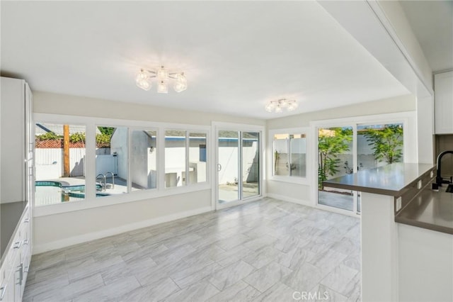 kitchen featuring white cabinets, kitchen peninsula, and a healthy amount of sunlight